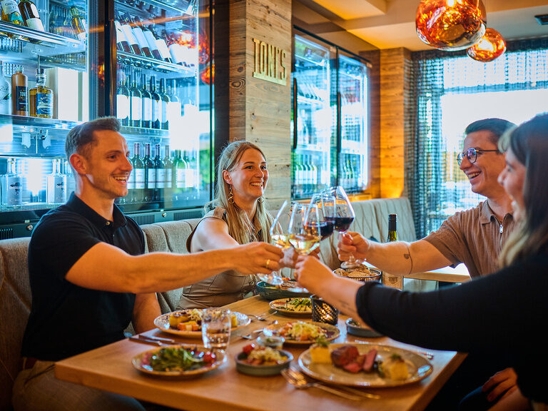 Eine fröhliche Gruppe genießt ein gemütliches Abendessen im Toni´s Gasthaus mit alkoholischen Getränken.