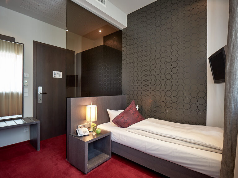 Ein Economy-Zimmer im TONIs by Wenisch mit Bett und einem funktionalen Schreibtisch.