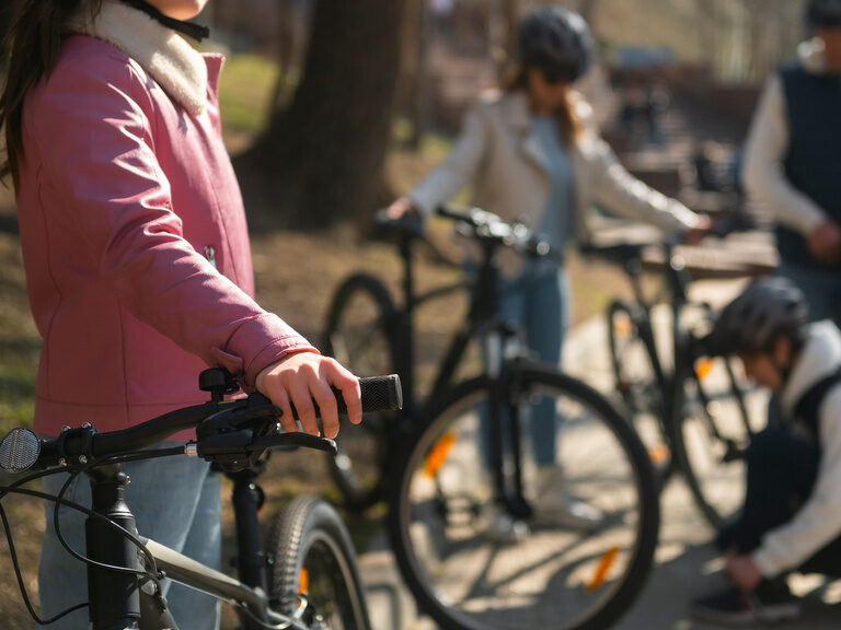 Mehrere Kinder mit Fahrradhelmen stehen mit ihren Fahrrädern auf einem Weg im Freien