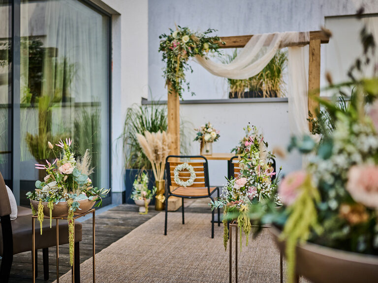 Outdoor-Trauung mit floraler Dekoration und elegantem Traubogen aus Holz