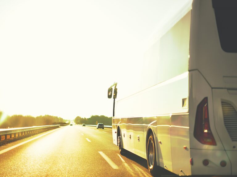 Reisebus fährt bei tief stehender Sonne auf einer Autobahn