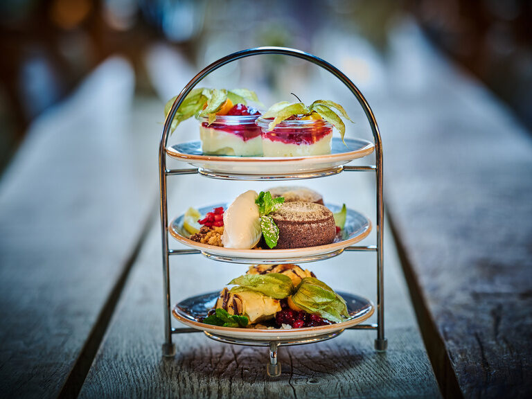 Ein dreistufiges Tablett mit Fingerfood auf einem Holztisch.
