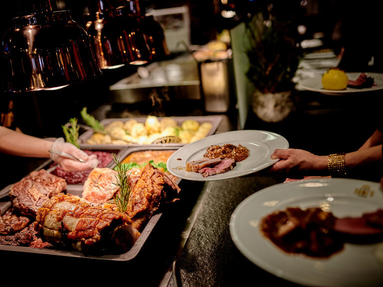 Eine Person gibt warmes Essen von einem Buffet aus.