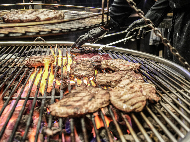 Mehrere Schweinefleischstücke brutzeln auf einem heißen Grill bis zum gewünschten Garpunkt.