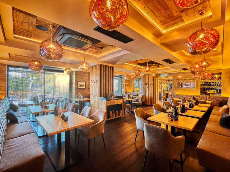 Ein modernes Restaurantdesign im TONIs by Wenisch mit geschmackvoller Beleuchtung und gemütlichen Sitzgelegenheiten.
