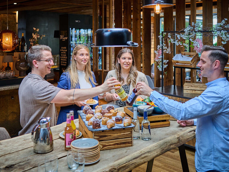 An einem gemütlichen Holztisch genießen Gäste im Restaurant TONIs by Wenisch ihr Frühstücksbuffet.