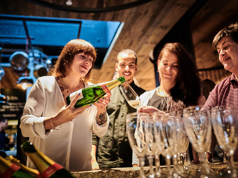 Eine fröhliche Gruppe sitzt zusammen bei Rotwein und genießt die entspannte Atmosphäre.