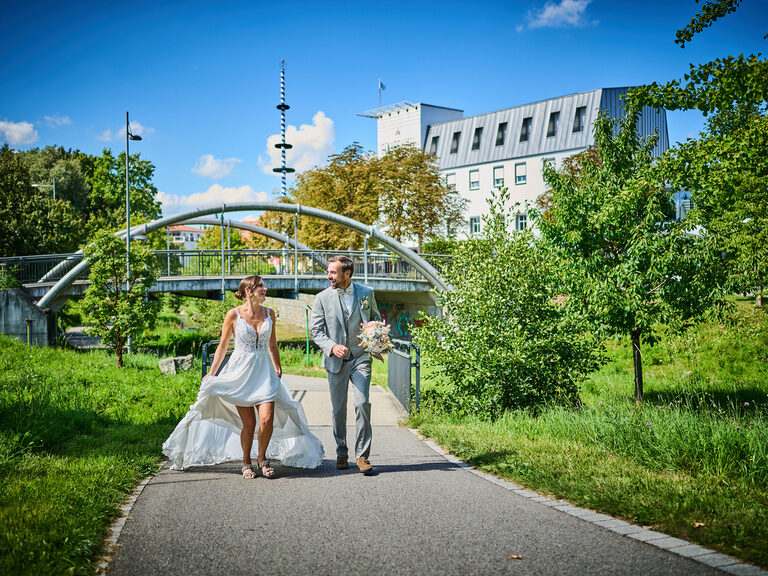 Brautpaar spaziert lachend durch Parklandschaft nach der Trauung im Sommer