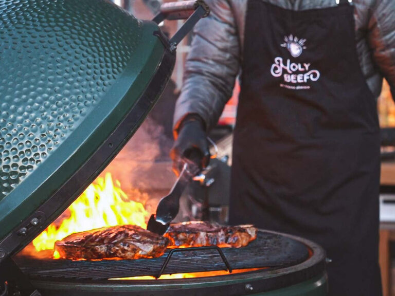 Eine Person kocht Fleisch auf dem Grill bei Holy Beef.