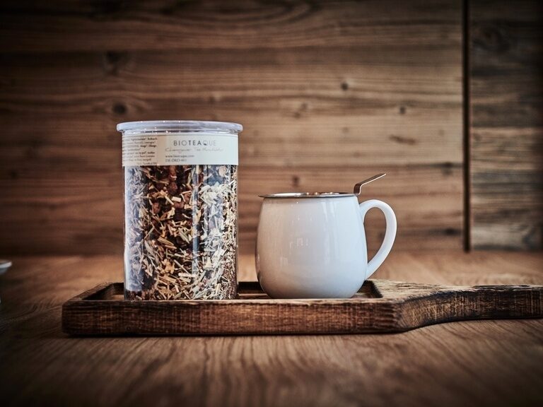 Ein Müslibecher steht auf einem Tisch neben einer Kaffeetasse.