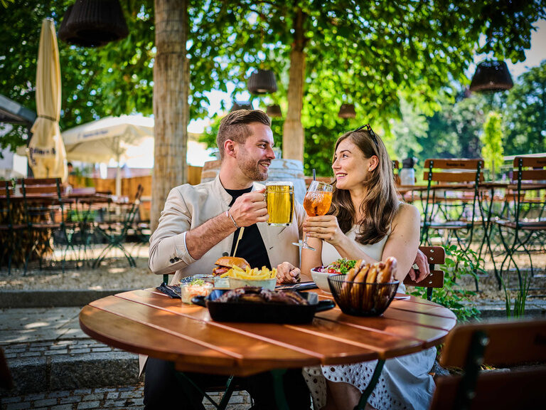 Zwei Personen genießen Bier an einem Outdoor-Tisch bei TONIs by Wenisch.