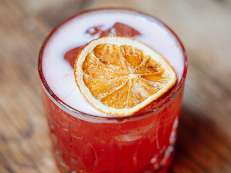 Ein erfrischendes rotes Getränk, verziert mit einer Orangenscheibe aus der Bar Auswahl.