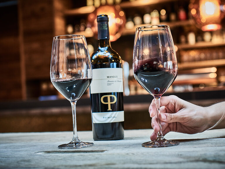 Eine Flasche Wein und zwei Weingläser stehen auf einem Tisch.