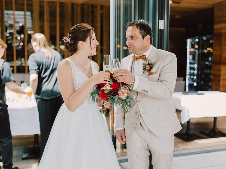 Ein Brautpaar stößt bei ihrer Hochzeit in Toni´s Eventlocation mit Sektgläsern an.