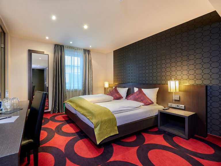 Das komfortable Standard Zimmer mit einem bequemen Bett und Fernseher für entspannte Abende im Genusshotel Wenisch