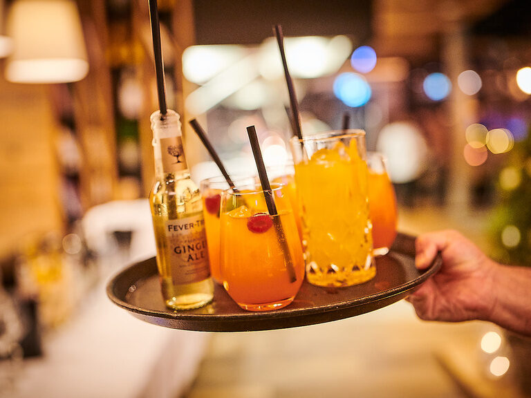 Ein Kellner serviert ein Tablett mit bunten Getränken auf einer Hochzeit im Toni´s Gasthaus.