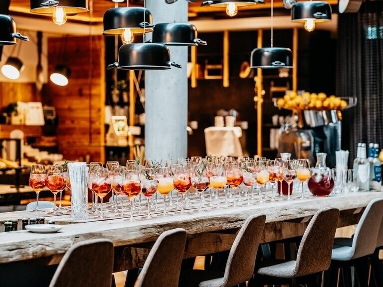 Eine große Tafel ist zu einem besonderen Anlass mit vielen gefüllten Gläsern eingedeckt.