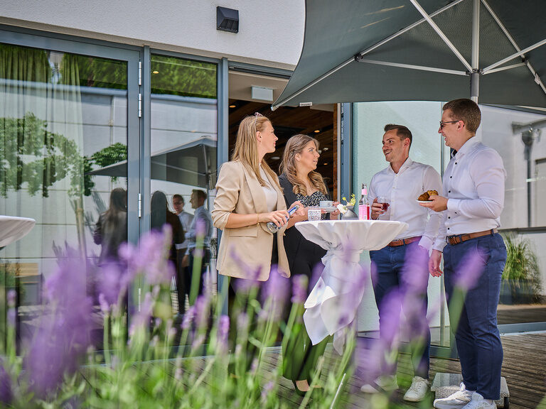 Vier Personen stehen am Eingang des Genusshotel Wenisch um einen Stehtisch.