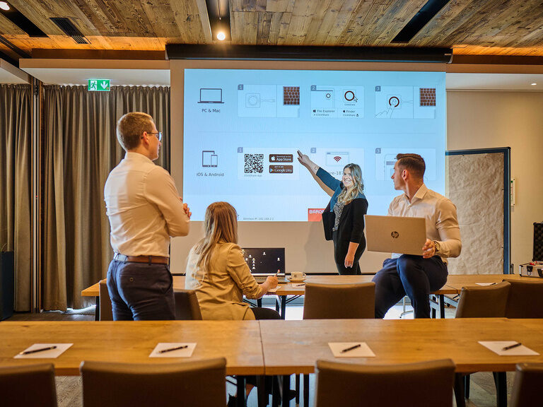 Eine Gruppe von Personen in einem Konferenzraum vor einer Leinwand