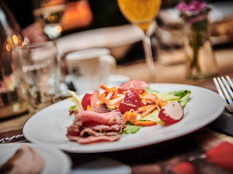 Ein Teller mit Wurst und Gemüse wie Radieschen steht auf einem gedeckten Tisch im Toni´s Gasthaus in Straubing.