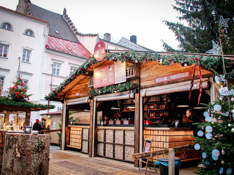 Ein prächtiger Tannenbaum strahlt vor einer Hütte auf einem Weihnachtsmarkt in Straubing.