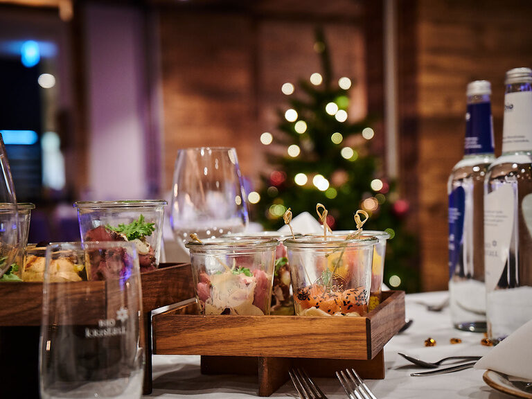 Ein festlich gedeckter Tisch vor einem geschmückten Weihnachtsbaum im Restaurant TONIs by Wenisch.